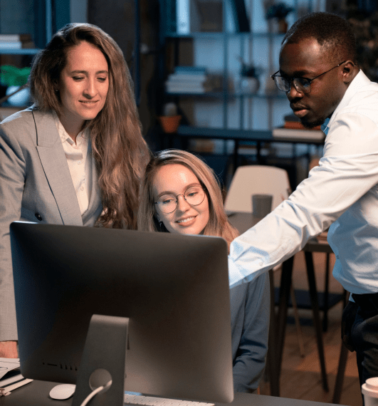 Employees discussing a project while looking at desktop.